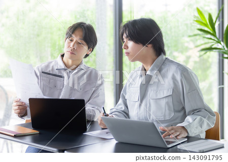 一名日本男員工正在開會,同時查看他的筆記型電腦和文件。 一名日本男員工正在開會,同時查看他的筆記型電腦和文件。 143091795