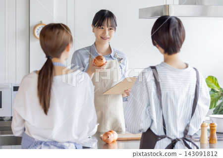 A Japanese woman explains cooking methods while holding an onion in a cooking class. A Japanese woman explains cooking methods while holding an onion in a cooking class. 143091812
