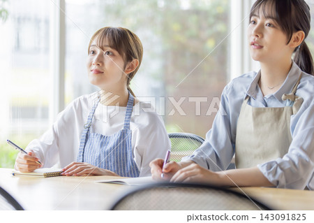 一位日本女性在烹飪課上邊聽老師講解邊做筆記。 一位日本女性在烹飪課上邊聽老師講解邊做筆記。 143091825