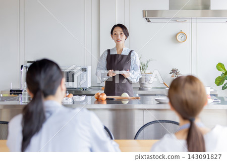 A Japanese female instructor explains while showing plates of food that have been plated during a cooking class. A Japanese female instructor explains while showing plates of food that have been plated during a cooking class. 143091827