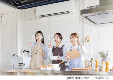 Three Japanese women in aprons, smiling and enthusiastic, at a cooking class. Three Japanese women in aprons, smiling and enthusiastic, at a cooking class. 143091878