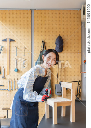 一位微笑的日本女子正在DIY工作室製作木椅。 一位微笑的日本女子正在DIY工作室製作木椅。 143091900