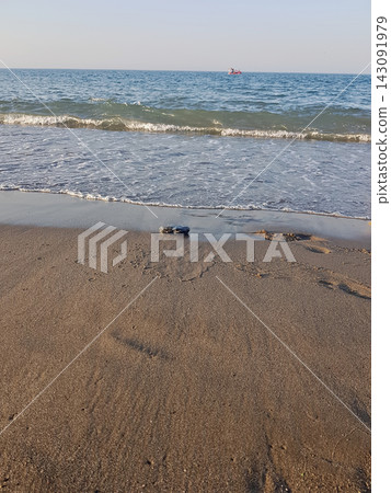 Gentle waves retreat across sunwarmed sand, leaving shimmering trails before drawing back to the sea Gentle waves retreat across sunwarmed sand, leaving shimmering trails before drawing back to the sea 143091979