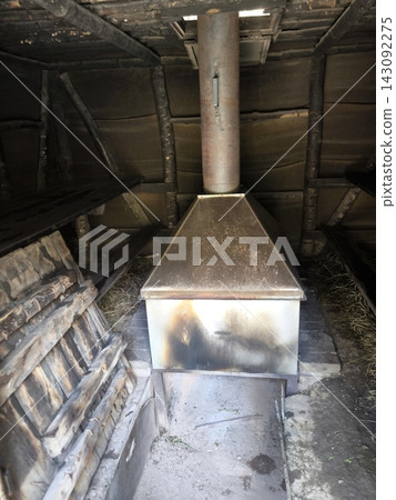 A wood-burning stove and chimney in the interior of a traditional Russian black bathhouse A wood-burning stove and chimney in the interior of a traditional Russian black bathhouse 143092275