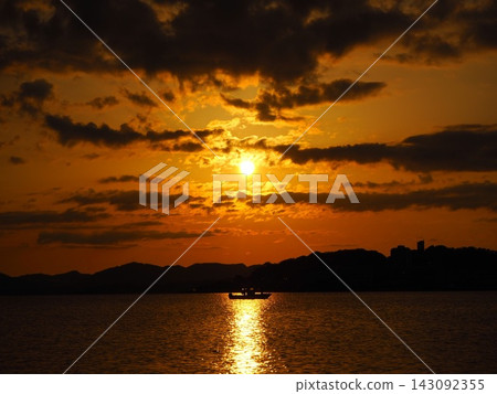 在島根縣松江市宍道湖上，一艘小船漂浮在一道光影中，映襯著壯麗的日落。 143092355
