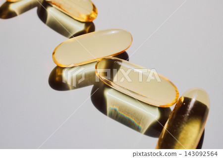 Golden gel capsules showing dietary supplement for wellness and healthcare Golden gel capsules showing dietary supplement for wellness and healthcare 143092564