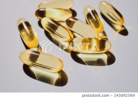 Golden gel capsules of fish oil providing essential omega-3 fatty acids for well-being Golden gel capsules of fish oil providing essential omega-3 fatty acids for well-being 143092569