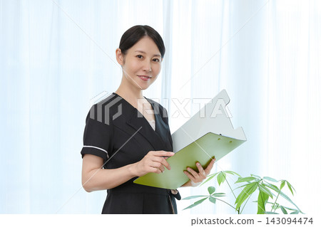 一位面帶微笑的整形外科工作人員正在查看記錄板。 一位面帶微笑的整形外科工作人員正在查看記錄板。 143094474