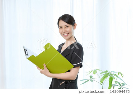 一位面帶微笑的整形外科工作人員正在查看記錄板。 一位面帶微笑的整形外科工作人員正在查看記錄板。 143094475