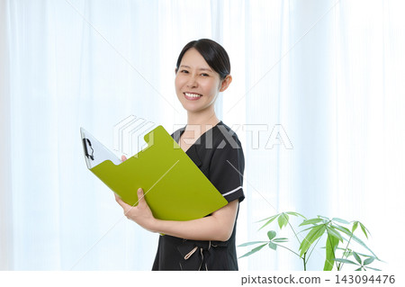 A smiling cosmetic surgery staff member checking a clipboard. A smiling cosmetic surgery staff member checking a clipboard. 143094476