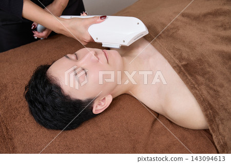 A man receiving facial hair removal treatment from a beauty staff member. A man receiving facial hair removal treatment from a beauty staff member. 143094613