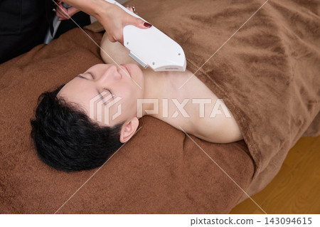 A man receiving facial hair removal treatment from a beauty staff member. A man receiving facial hair removal treatment from a beauty staff member. 143094615
