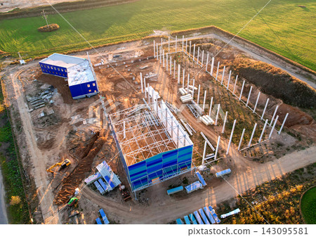Aerial view of industrial construction site with steel frame and blue modular buildings Aerial view of industrial construction site with steel frame and blue modular buildings 143095581