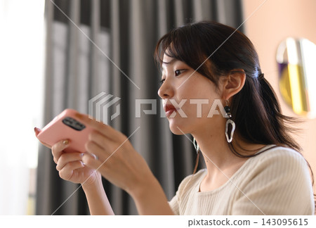 一位女士查看智慧型手機螢幕時的側臉。 一位女士查看智慧型手機螢幕時的側臉。 143095615