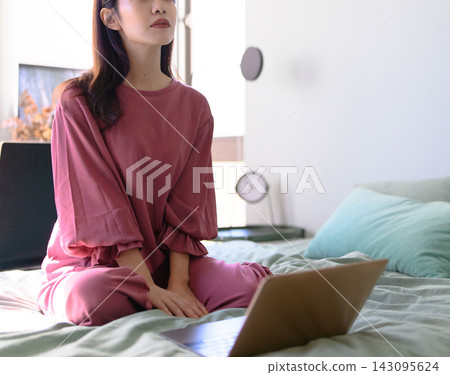 一位女子躺在床上,看著筆記型電腦,陷入沉思。 一位女子躺在床上,看著筆記型電腦,陷入沉思。 143095624