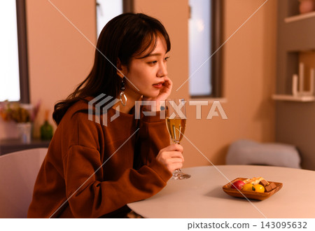 一位女子陷入沉思，手中拿著一杯香檳。 143095632