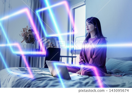 A woman sitting in bed in front of a laptop A woman sitting in bed in front of a laptop 143095674