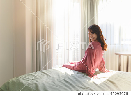 A morning scene of a woman relaxing and smiling in bed. A morning scene of a woman relaxing and smiling in bed. 143095676