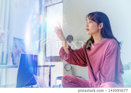 A woman in bed, using her laptop, points to space and thinks. A woman in bed, using her laptop, points to space and thinks. 143095677