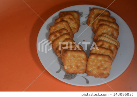 Square crispy crackers arranged in a u-shape on a white plate with floral patter Square crispy crackers arranged in a u-shape on a white plate with floral patter 143096055