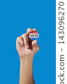 a man holds a vote badge between his fingers 143096270