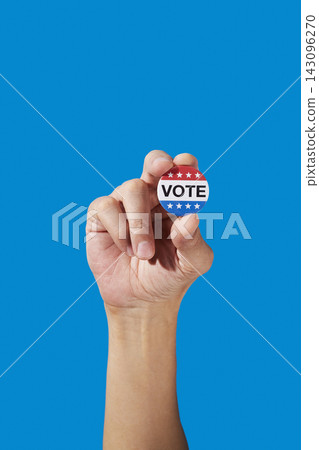 a man holds a vote badge between his fingers a man holds a vote badge between his fingers 143096270