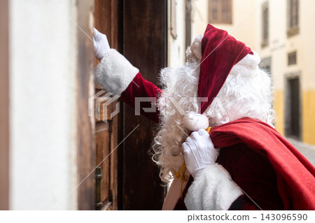 Santa Claus knocking on a wooden door Santa Claus knocking on a wooden door 143096590