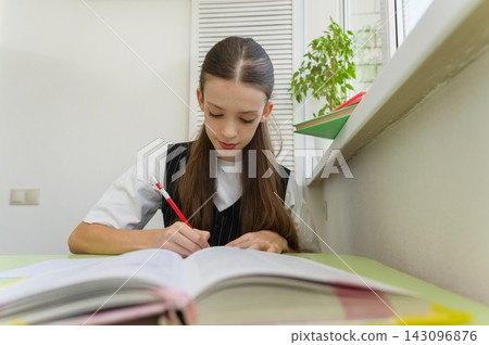 Teenage high school girl studying at a desk in her room. Teenage high school girl studying at a desk in her room. 143096876