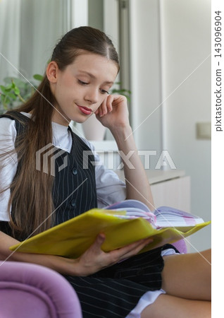 Teenage Schoolgirl Reading Book While Relaxing at Home Teenage Schoolgirl Reading Book While Relaxing at Home 143096904