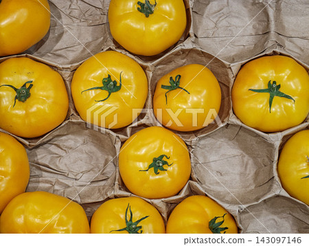 Fresh Yellow Tomatoes Arranged in Cardboard Produce Tray - illustrating fresh produce, grocery packaging, harvest and plastic-free food packaging concepts. Fresh Yellow Tomatoes Arranged in Cardboard Produce Tray - illustrating fresh produce, grocery packaging, harvest and plastic-free food packaging concepts. 143097146