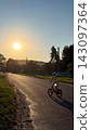 Young girl cycling on rural road at sunset 143097364