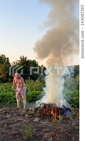 Man burning garden waste in field during agricultural work Man burning garden waste in field during agricultural work 143097365