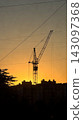 Tower crane silhouette at sunset constructing urban skyline 143097368