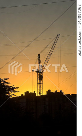 Tower crane silhouette at sunset constructing urban skyline Tower crane silhouette at sunset constructing urban skyline 143097368