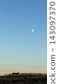 Cow silhouette in field with daytime moon 143097370