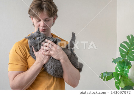 Caring for pet cat at home . Man Spending Time with His Cat at Home Caring for pet cat at home . Man Spending Time with His Cat at Home 143097972