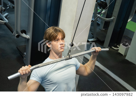 Pulling man cable machine exercise. Workout Routine With Personal Trainer Pulling man cable machine exercise. Workout Routine With Personal Trainer 143097982