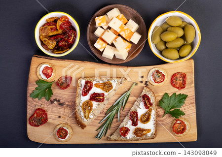 Snacks and sandwiches with dried tomatoes on wooden board. Snacks and sandwiches with dried tomatoes on wooden board. 143098049