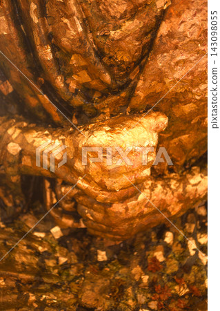 Detailed view of a textured, golden sculpture featuring a grasping hand Detailed view of a textured, golden sculpture featuring a grasping hand 143098055