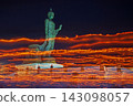 Buddha statue illuminated by flickering lights against a night sky 143098057