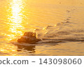 A small boat navigating through golden waters at sunset 143098060