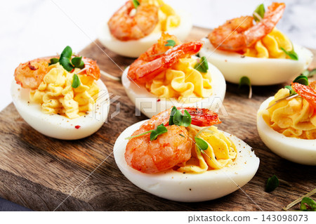 Boiled eggs stuffed with yolk and seasoned with mayonnaise, stuffed eggs with shrimp, on a wooden chopping board, selective focus, close-up, no people, Boiled eggs stuffed with yolk and seasoned with mayonnaise, stuffed eggs with shrimp, on a wooden chopping board, selective focus, close-up, no people, 143098073