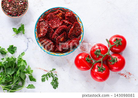 Dried tomatoes, in a bowl with fresh herbs and spices, on a white marble surface, no people Dried tomatoes, in a bowl with fresh herbs and spices, on a white marble surface, no people 143098081