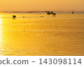 Golden sunset over the calm sea with traditional stilt houses and small fishing boats at dusk 143098114