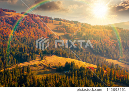 sunset over mountainous rural landscape of ukraine in autumn. picturesque highland woods. grassy meadow. carpathian countryside scenery with colorful forest and pasture on a hill under rainbow sunset over mountainous rural landscape of ukraine in autumn. picturesque highland woods. grassy meadow. carpathian countryside scenery with colorful forest and pasture on a hill under rainbow 143098361