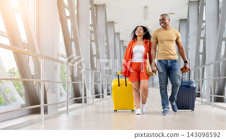 Joyful couple looking upward while walking through bright airport walkway,holding hands 143098592