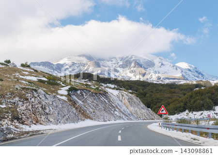 Mountain road with snowy peaks in the background Mountain road with snowy peaks in the background 143098861