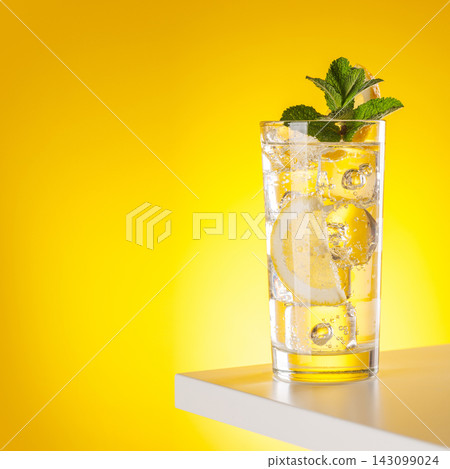 Sparkling water with lemon and ice on yellow background refreshment Sparkling water with lemon and ice on yellow background refreshment 143099024