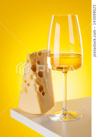 Glass of white wine with cheese on yellow background food pairing concept Glass of white wine with cheese on yellow background food pairing concept 143099025