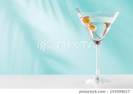 Classic martini cocktail with olives in glass on blue background Classic martini cocktail with olives in glass on blue background 143099027